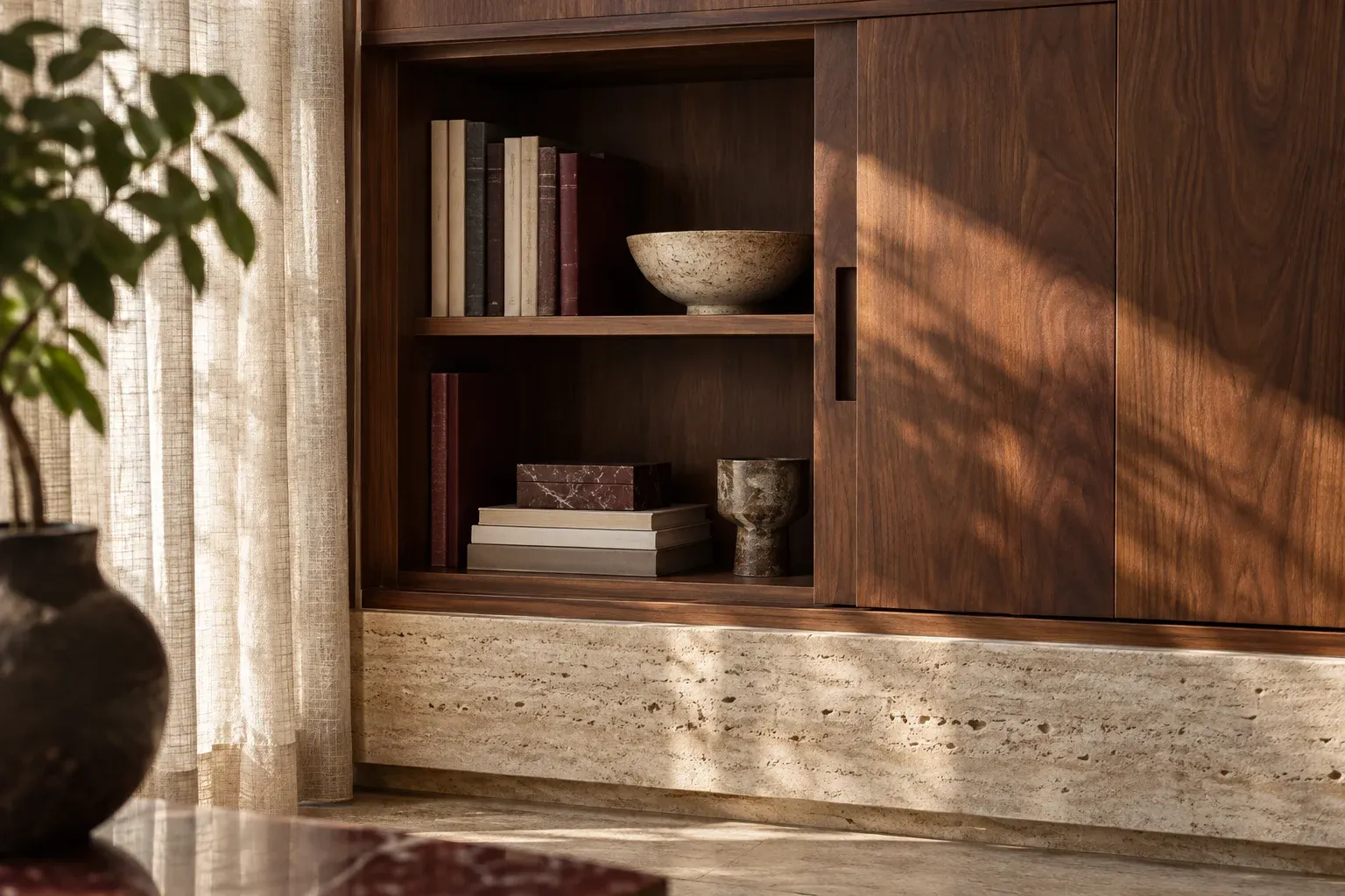 Illustrative walnut joinery detail with a sliding door, books and a travertine ledge